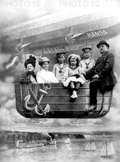 Family in balloon dummy, 1910s, A family sits in the gondola of an airship with the name Hansa over