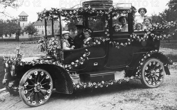 Wedding car with flowers, 1910s, A happy family sits outside in a vintage car decorated with