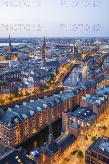 Aerial view of the Speicherstadt Hamburg at blue hour with churches and Alster in the background,