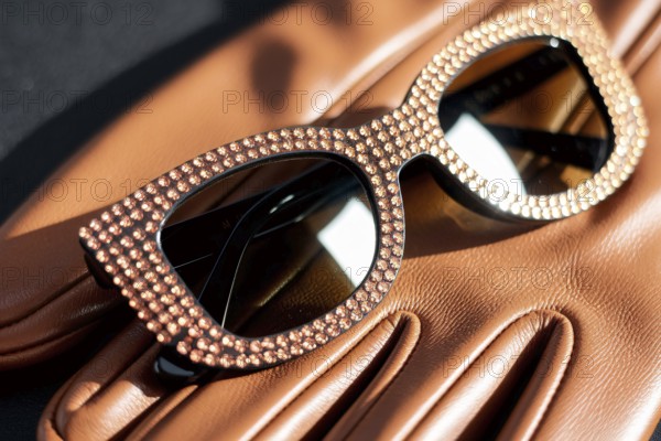 Rhinestone sunglasses resting on leather glove. A symbol of luxury, glamour, and timeless elegance.