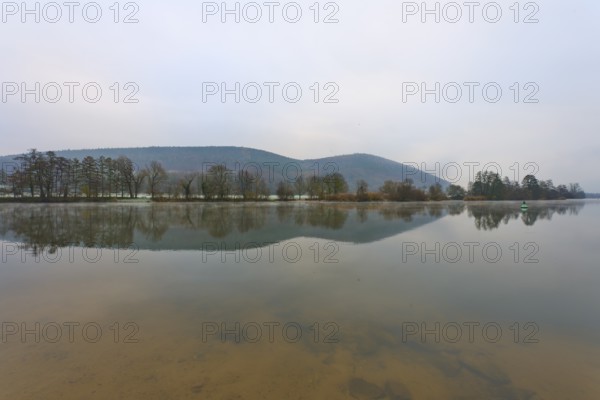 Wide river with calm water surface, mountains in the background, cloudy sky, Laudenbach, Main,