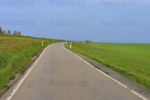 Country road leads through wide green fields under a clear sky, Hornbach, Walldürn, Odenwald,