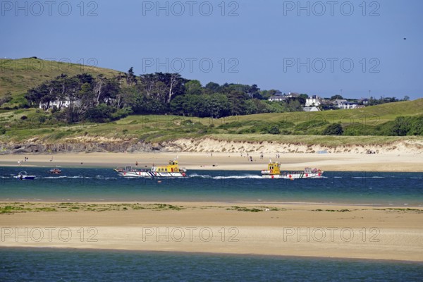 Two boats on the sea with green hills and a clear sky in the background, Padstow, Cornwall,
