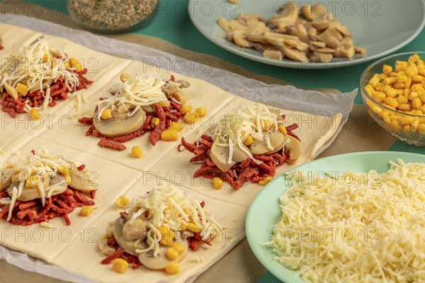 Sliced dough squares with tomato paste, bacon, mushrooms, sweetcorn and cheese alongside other