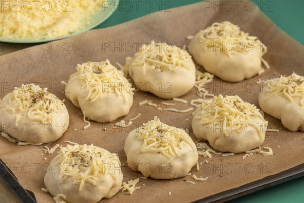 Raw pizza, balls with grated cheese and oregano on baking paper, ready for the oven