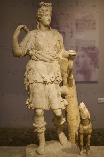 Ancient sculpture of Artemis with dog, in classical traditional costume and pose, Archaeological