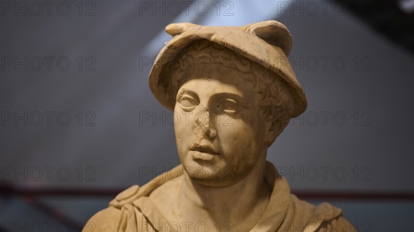 Ancient marble bust of a man wearing a Roman hat, on display in the museum, Hermes, Archaeological