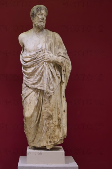 Marble statue of a bearded man in classical pose, surrounded by cloths, Archaeological Museum, Kos