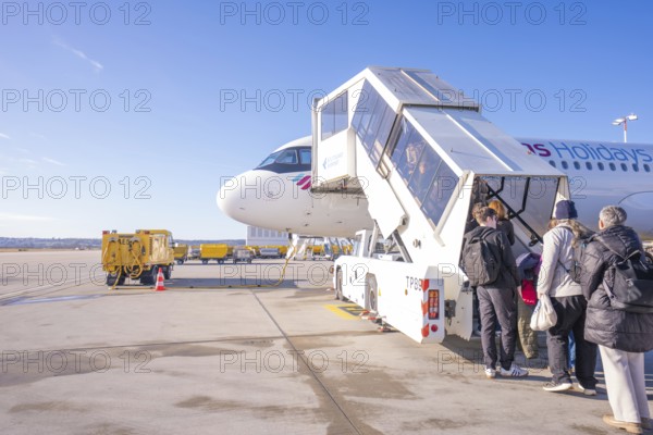 People board an airplane via a gangway, clear blue sky in the background, London, United Kingdom,