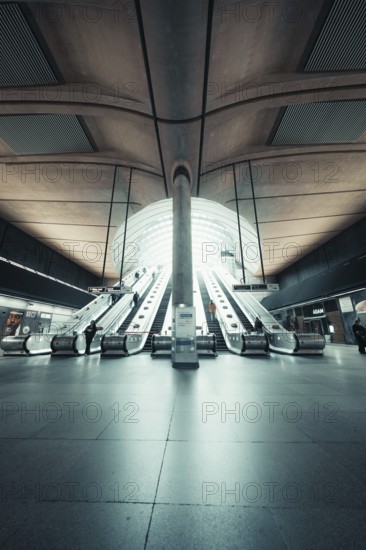 Bright, symmetrical escalator system in a modern station concourse, Canary Wharf Station, London,