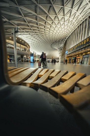Modern station concourse with eye-catching ceiling patterns and people in a lively atmosphere,