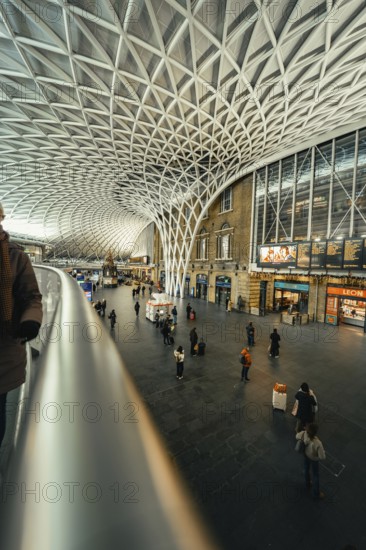 Large, modern train station with impressive glass roof and scattered travelers, King's Cross