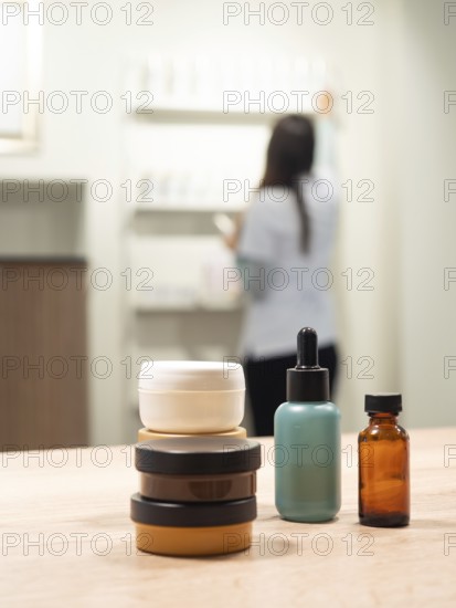 Skincare jars and serum bottles on a wooden table with an aesthetician arranging products in a