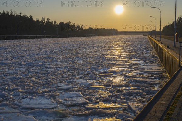 Frozen channel at sunset with reflecting light and wooded banks, ice floes, Elbe-Havel Canal,