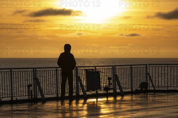 Traveler standing at the railing and looking at the sea at sunset, Finland ferry Helsinki to