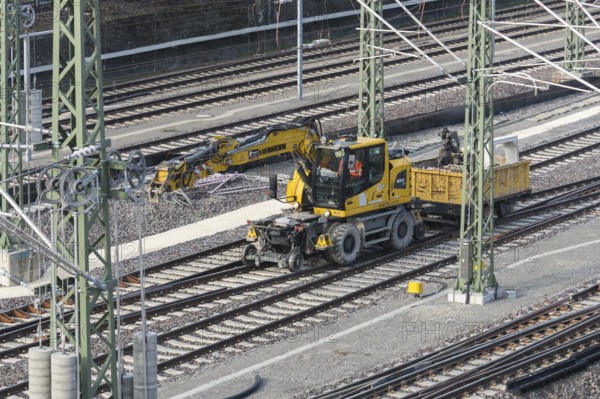 A yellow rail vehicle on a railway line surrounded by construction site equipment, Untertürkheim
