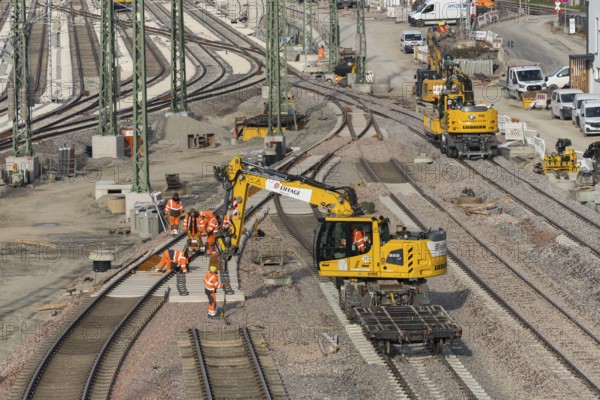 Track construction on a construction site with groups of construction workers and a yellow