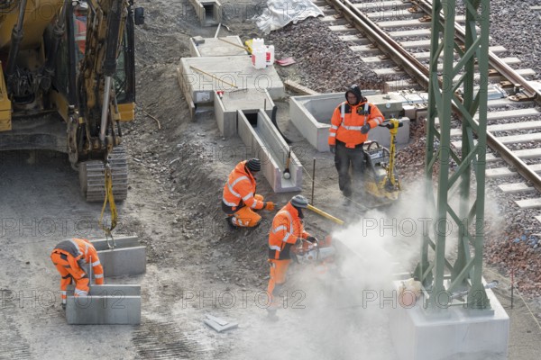 Construction workers in protective clothing carry out work on rails, accompanied by construction