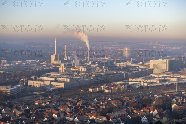 Aerial view of a city at dusk, with industrial structures and suburban houses, sky and smoke