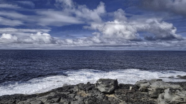 Rough sea under cloudy sky meets rocky coast. Atmospheric and wild with moving waves, Yaiza