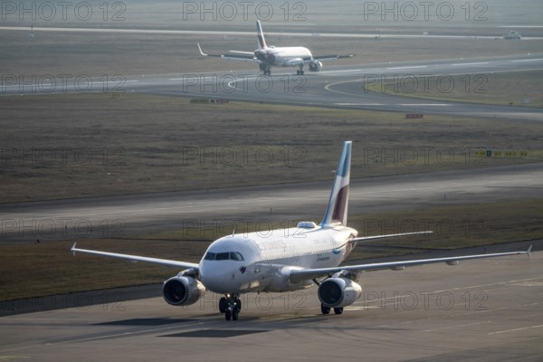 Eurowings Airbus after landing on the taxiway to the terminal, plane taking off, to Cologne/Bonn