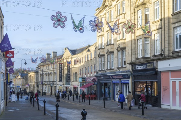 Christmas street decorations hang above quiet shopping street in January, town centre of