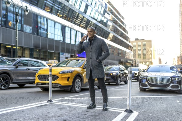 Man standing on a new york city street, making a phone call while surrounded by urban traffic and