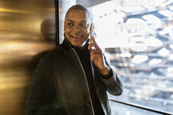 Smiling professional man engaging in a phone conversation, using a smartphone while standing
