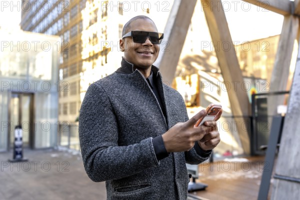 Businessman in modern sunglasses looking at new horizons while standing in a busy urban setting,