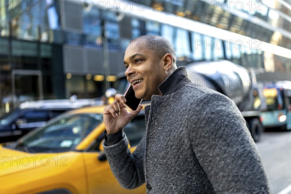 Young black businessman is walking on a city street in manhattan, new york, laughing while having a
