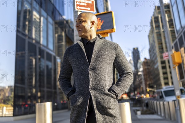 Young man smiling confidently as he walks through manhattan's financial district in smart casual