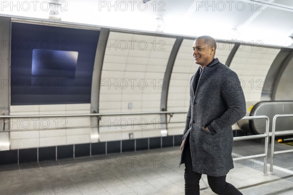 Businessman smiling and walking purposefully through a modern subway station, feeling confident and