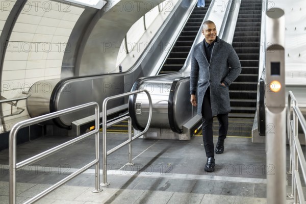 Professional man commuting through a modern subway station, coming down an escalator with a