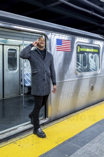 Happy professional man smiling and talking on smartphone while stepping onto a manhattan subway