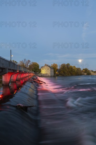 Illuminated Moulin Neuf water flow control dam and walkway over Des Mille-Iles river plus New Mill