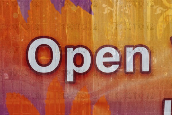 Close-up of the word open spelled out in white letters outlined in maroon color on textile banner,