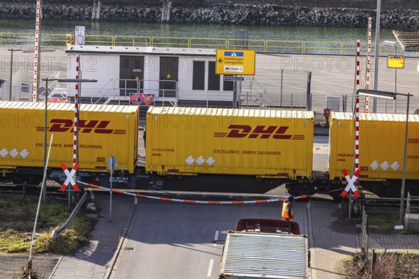 Freight train loaded with yellow container from DHL. Railway crossing in the port area of Mannheim,