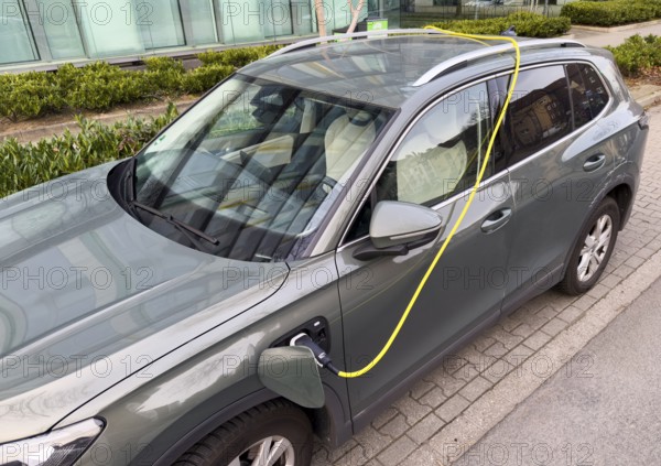 An e-car is charged at a charging station in Düsseldorf, the charging cable is stored over the roof