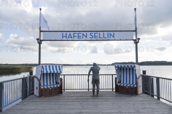 Viewing platform with two beach chairs and a sculpture that looks like a person, sign with flag,