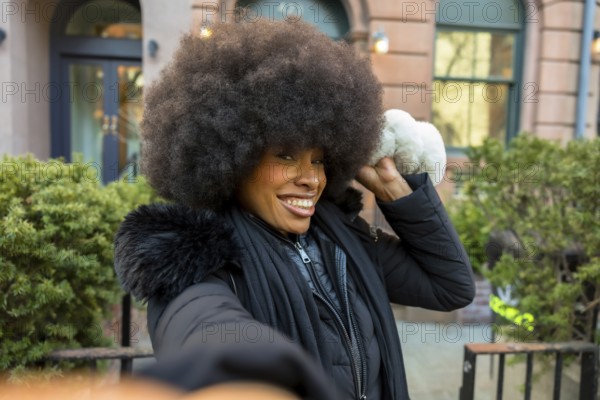 African american woman with afro hairstyle smiling and preparing to throw an artificial snowball