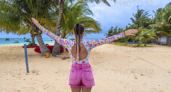 Woman with arms outstretched on white sand beach in the maldives, soaking up sunshine and turquoise