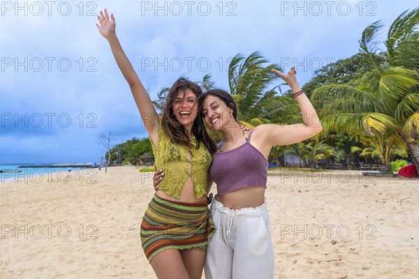 Two smiling young women friends embracing, raising arms, and expressing joy, celebrating their fun