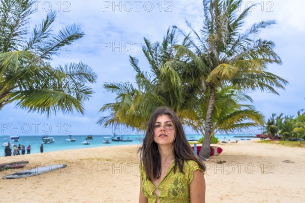 Woman standing on a tropical beach in the maldives, surrounded by sand, palm trees, and turquoise