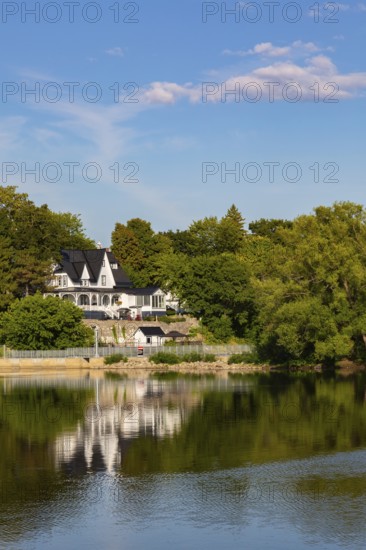 19th century multistory old white clapboard home with black rooftops and backyard built on edge of