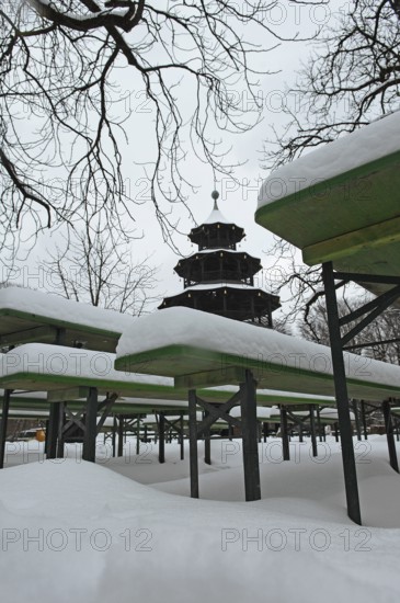Winter in the English Garden, snow-covered beer garden tables and benches, Chinese Tower, Munich,