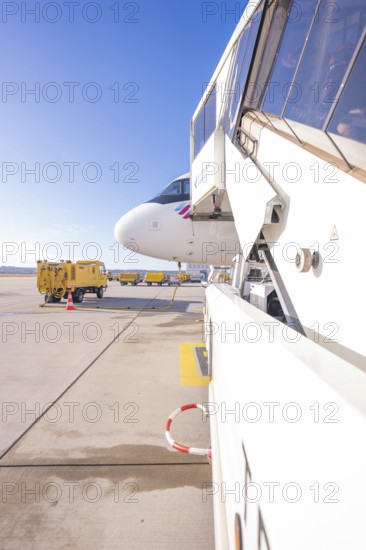Close-up of an airplane staircase at an airport with Eurowings aircraft in the background,