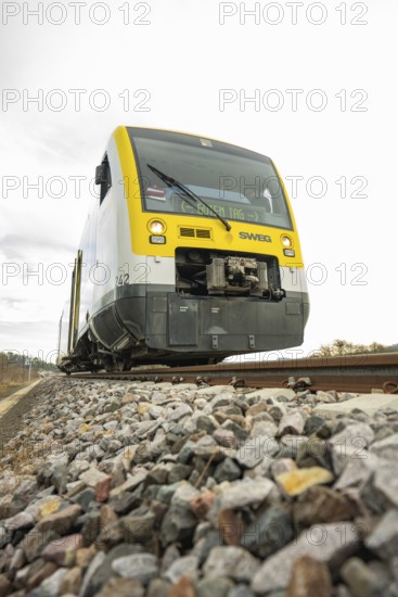 SWEG train on rails with pebbles in the foreground under cloudy sky, taking off the Hermann
