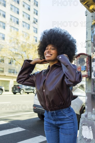 Young african american woman with afro hair smiling confidently on a sunny manhattan street,