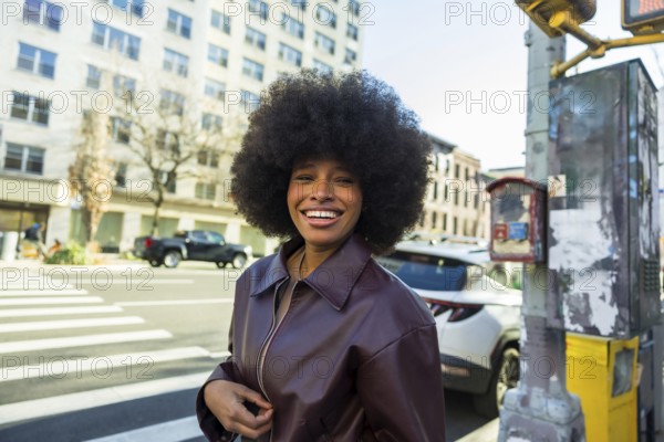 Happy young african american woman smiling brightly, standing on a new york city street with an