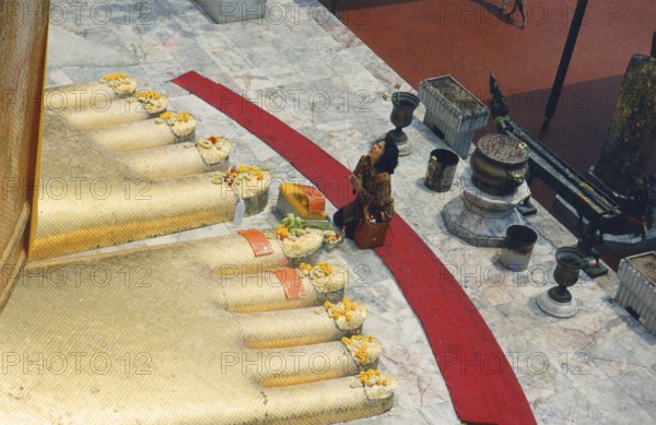 The huge golden Buddha at Wat Indravihan. A Buddhist woman prays at the feet of the big standing